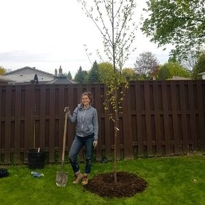 Young woman with a shovel next to a recently planted tree(© 2019 Adriana Rezai-Stevens / LEAF)