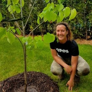 Young woman squatting next to a tree(© 2019 Adriana Rezai-Stevens / LEAF)