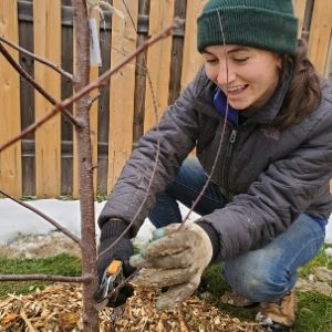 Woman pruning low branches of a young tree(© 2019 Adriana Rezai-Stevens / LEAF)