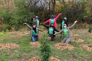 six people celebrating surrounded by young recently planted trees