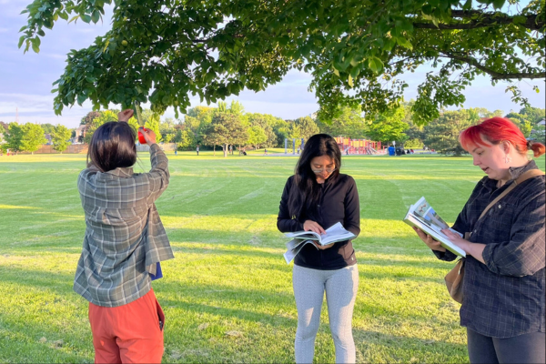 Three YUFL members use their tree identification books to determine the species of a tree to prepare for their tree tour.