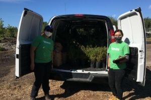 Two women standing next to a white van filled with shrubs(© 2020 Erin MacDonald / LEAF)